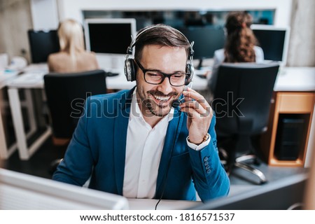 Handsome male customer service agent with headset working in call center. Royalty-Free Stock Photo #1816571537