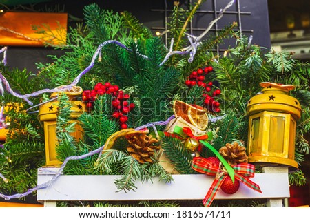 Christmas decor hanging on wall. Fir branches, cones, dried oranges, toys and lanterns in wooden box. Selective focus