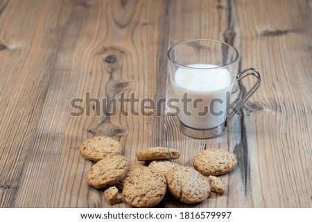 Tasty homemade sesame cookies with a cup of milk over a wooden table