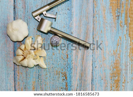 Garlic with garlic press on old wooden background