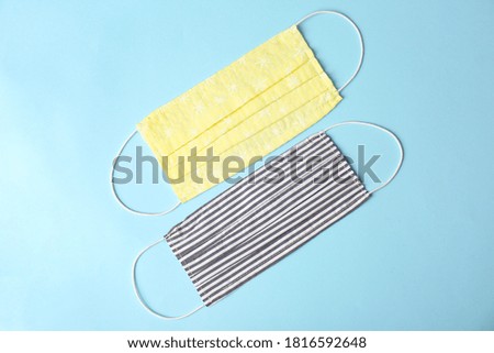 Homemade protective face masks on light blue background, flat lay