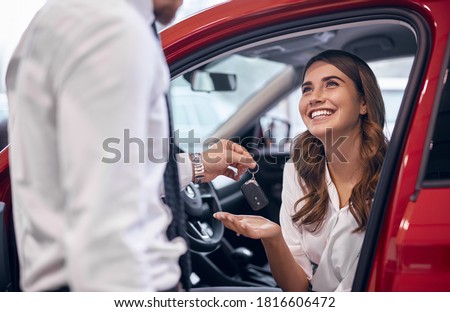 Crop male manager giving car keys to delighted woman in new car while working in dealership Royalty-Free Stock Photo #1816606472