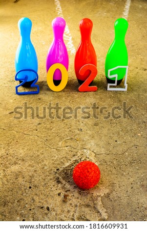 kids bowling pins with new year numbers 2021 on cement floor with red ball