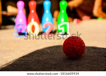 kids bowling pins with 2021 inscription - new year numbers on cement floor with red ball in the foreground