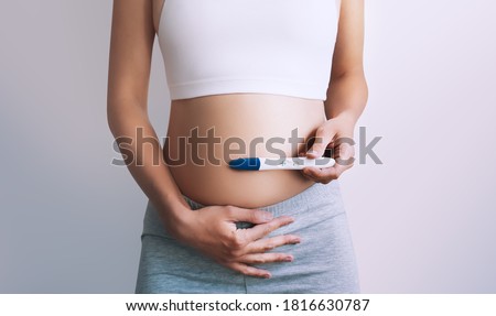 Young woman holding pregnancy test in hands and hugging her belly. Concept of pregnanc, gynecology, medical test, women health. Royalty-Free Stock Photo #1816630787