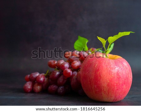 The picture of Japanese Fuji Apple with leaves. and red grapes with leaves isolated on a black background.