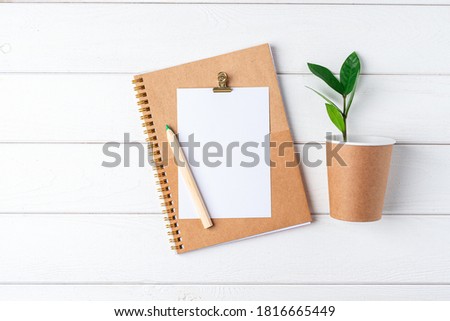 Desktop mockup planner. Flat lay of white wooden table background. Top view green sprout leaves, coffee cup, blank, craft Notebook. Zero waste, eco friendly, natural organic concept.