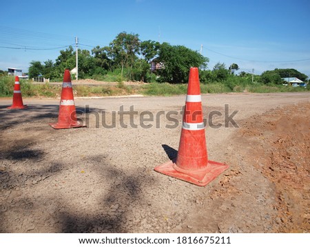 Old red and white traffic cones on the road. Three plastic cones block the road from passing through the inner construction site. Focus close and choose the subject.