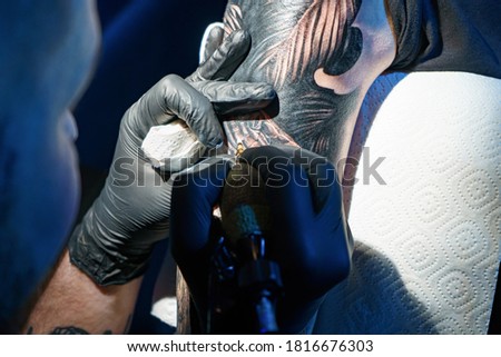 Image of tattooer doing black tattoo of snake for woman