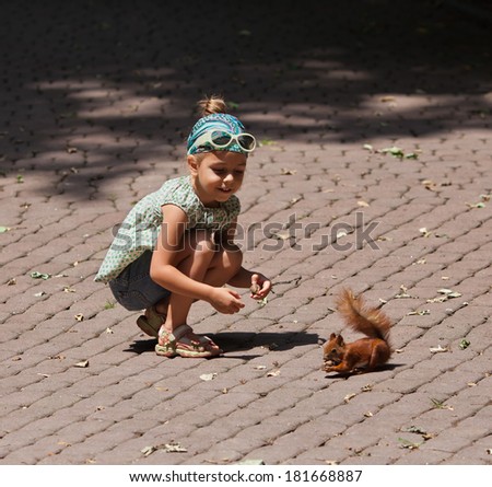 Cute little girl feeding squirrel at park