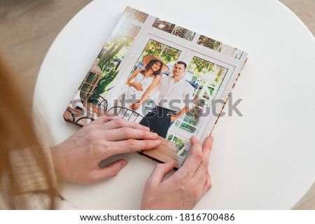 woman hold in hands photo book (paper with a grainy structure) from family pregnancy photo shoot. beautiful and convenient storage of photos. memory of important period.