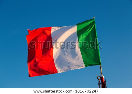 National flag of Italy waving into a blue sky background.