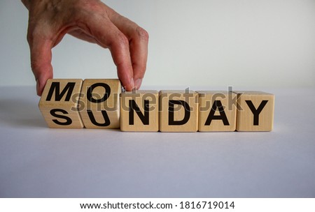 Hand is turning a cube and changes the word Sunday to Monday.  Beautiful white background, copy space. Concept.
