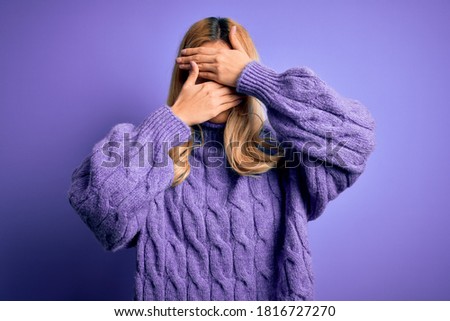 Young beautiful blonde woman wearing casual turtleneck sweater over purple background Covering eyes and mouth with hands, surprised and shocked. Hiding emotion Royalty-Free Stock Photo #1816727270