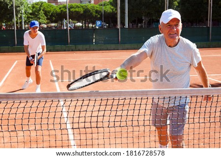 mature man and young man playing tennis court