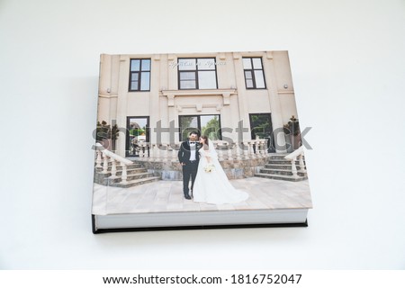 closed wedding photobook (paper with a grainy structure) on a white table. convenient, beautiful and long-lasting storage of photos. (Russian names Artyom and Arina are written on cover)
