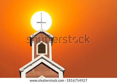 Cross in front of the church during golden hour.