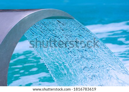 Swimming pool waterfall jet. Close up photo. Selective focus.