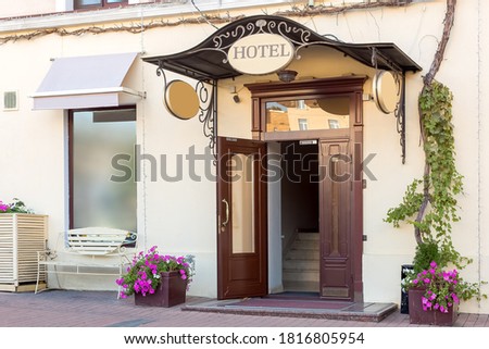 entrance door with a threshold and a visor with a hotel sign on the facade of the building with a flowerpot, european cityscaep nobody.