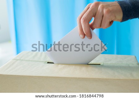 Man's hand holding a ballot paper for voting at a polling station during elections or referendum. Royalty-Free Stock Photo #1816844798