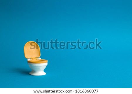 White toilet with an orange lid on a blue background in honor of world toilet day on November 19, which is dedicated to public toilets and their maintenance Royalty-Free Stock Photo #1816860077