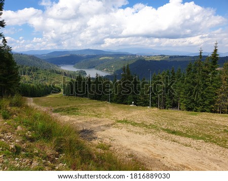 Marisel ski slope and Belis lake in summer on sunny day, Romania. Apuseni mountains scene, Cluj county, Transylvania, Romania. Pine tree forest, white clouds and blue sky nature landscape scene