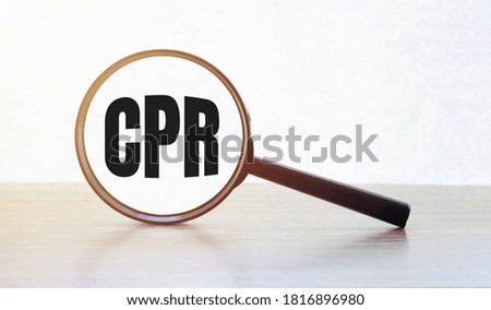 Magnifying glass with text CPR on wooden table.