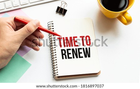 Hand with red pen. Cofee cup. Stick. Keyboard and white background. Time to renew sign in the notepad