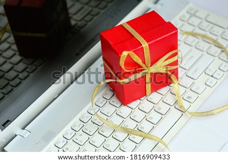Red gift box with a bow on a white computer background.Christmas shopping online on the Internet, discounts.Happy New Year!Buying gifts for the holiday! The 8th of March!Valentine's day!happy birthday