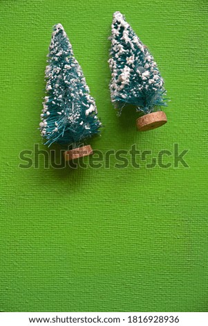 Two ornament snowy Christmas trees on upper left hand corner of green vertical background