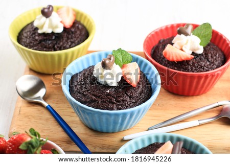 Chocolate Steam Cake on Colourful Ramequin, Topped with Strawberry, Mint Leaves, and Whipcream. On Wooden Background, Horzontal Picture