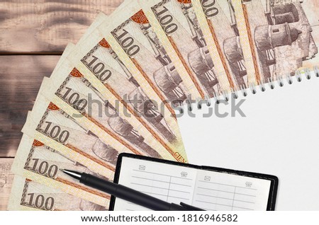 100 Dominican peso bills fan and notepad with contact book and black pen. Concept of financial planning and business strategy