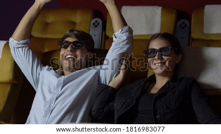 Man and woman in the cinema watching a movie with 3D glasses. with interest looking at the screen, exciting and eating popcorn