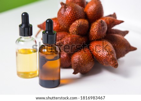 Bottle of extract with Fresh Salacca zalacca or Salak fruits white background.
