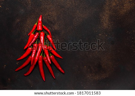 New year symbol: xmas tree made from red hot chilli peppers on dark background. Culinary christmas card with space for text top view
