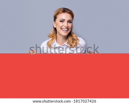 Very happy excited, laughing business woman in confident clothing showing blank red colour banner signboard. Success and advertising concept. Copy space empty place for advertisement text. Blond girl.