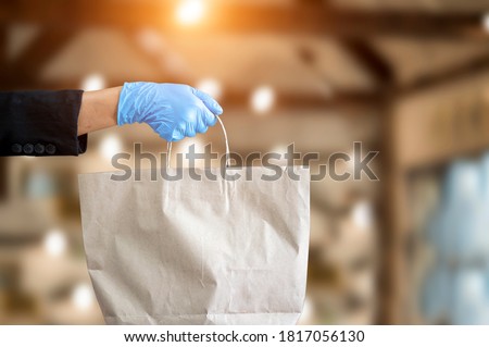 Small business and service concept with young woman Wearing blue gloves Filed paper bag with take away drink in cafe Royalty-Free Stock Photo #1817056130