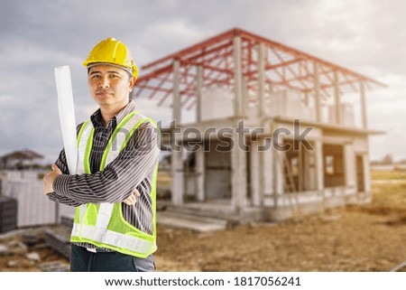 Portrait of asian business man construction engineer worker in protective helmet and blueprints paper on hand at house building site background