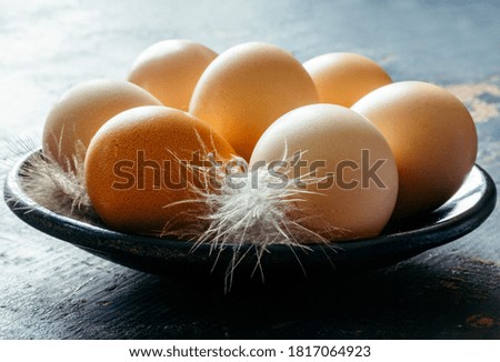 fresh chicken eggs and feathers in a plate on the table in a rustic morning