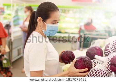 Asian woman long hair wearing protective face mask  in supermarket department store. Female, looking grocery to buy  some fruit. New normal after covid-19. Family concept.