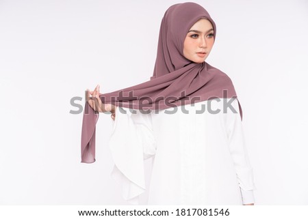 Close up portrait of a beautiful Muslim female model wearing white dress with dark chocolate color hijab isolated over white background. Studio fashion and beauty make up concept.