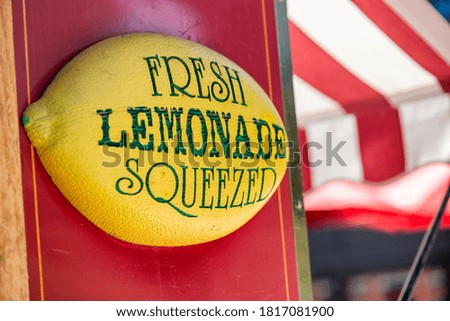 Fresh squeezed lemonade sign with white and red tent on background.