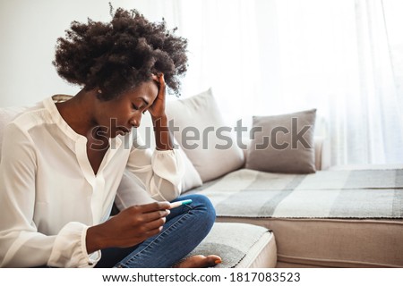 Shot of a young woman looking at the results on her pregnancy test. I can't be pregnant now. Sad and worried woman with a pregnancy test on bed. Woman holding pregnancy test