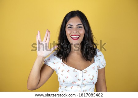 Beautiful woman over yellow background doing hand symbol
