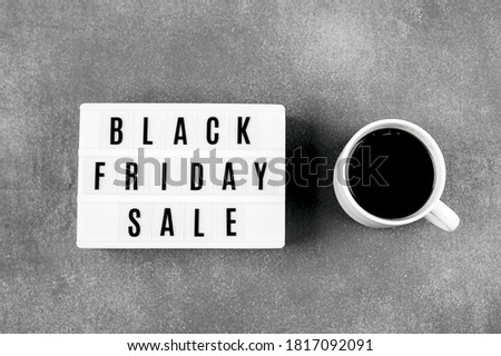 Black friday sale word on lightbox and cup of coffee on red background table. Flat lay, top view.
