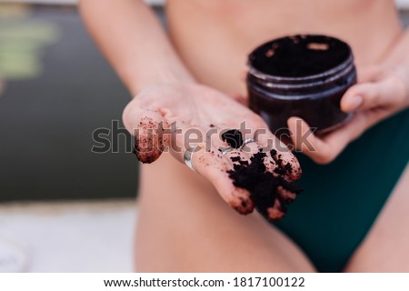 Outdoor portrait of fit woman in blue bikini at spa holding coffee scrab applies on slim body. Close no head shot.  