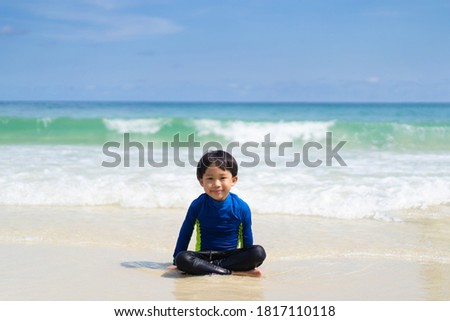 A boy is playing in the sand and swimming at the beach at an island in Thailand
