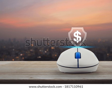 Dollar with shield flat icon on wireless computer mouse on wooden table over blur of cityscape on warm light sundown, Business money insurance and protection online concept