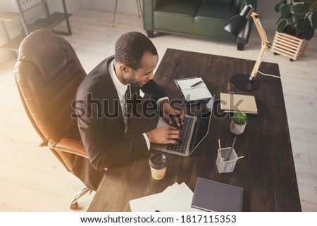 Profile photo of handsome dark skin business man guy notebook table chatting colleagues read corporate report insurance agent wear suit sit chair modern interior office indoors
