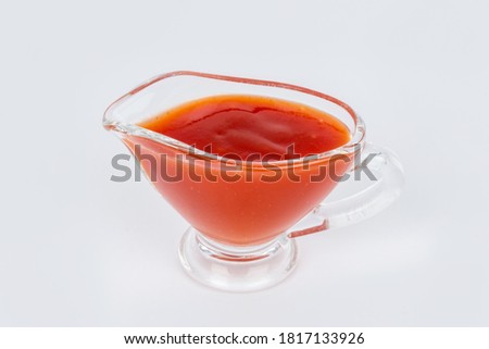 Sweet and sour sauce in a transparent gravy boat shot on a white background Royalty-Free Stock Photo #1817133926
